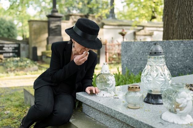 Free photo woman mourning a grave at the cemetery