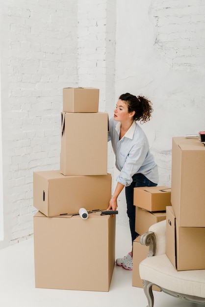 Free photo woman moving stack of boxes