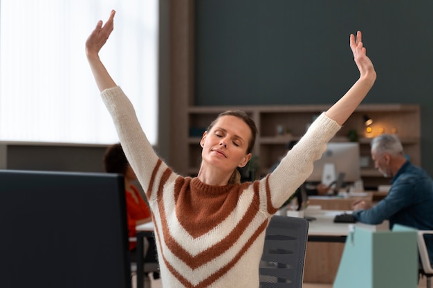 Free photo woman at the office stretching during a work day