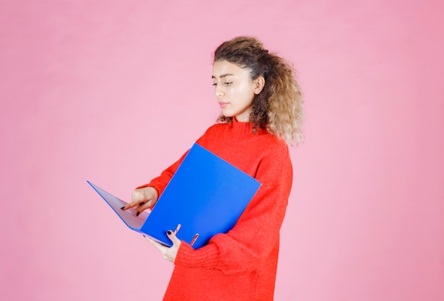 Free photo woman opening a blue report folder and looks thoughtful.