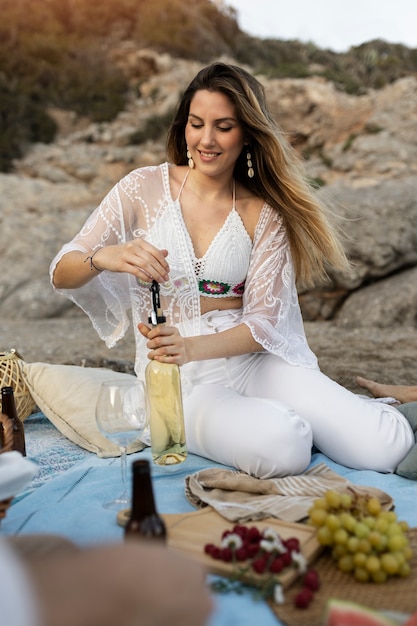 Free photo woman opening bottle of wine at the beach