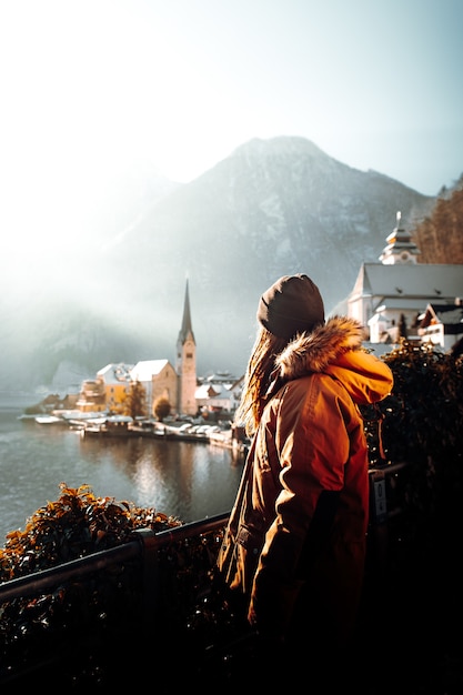 Free Photo woman in orange jacket standing on brown wooden dock during daytime