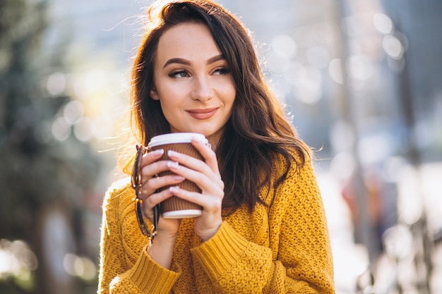 Woman in orange sweater drinking coffee