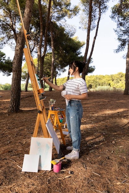 Free photo woman outside in nature painting on canvas