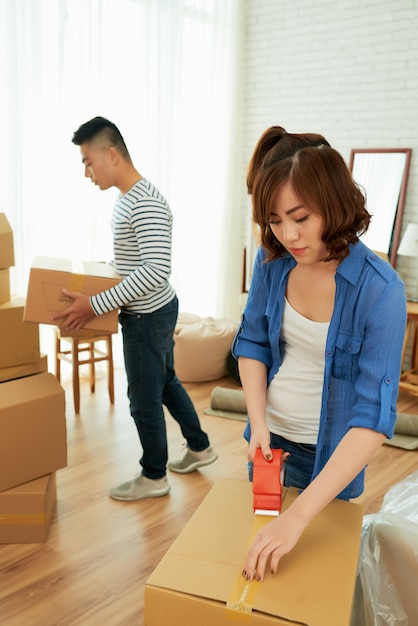 Woman packing boxes with her husband carrying packages