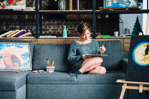 Woman painting on couch