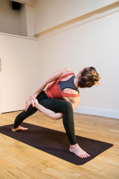 Woman performing bound side angle pose on exercise mat