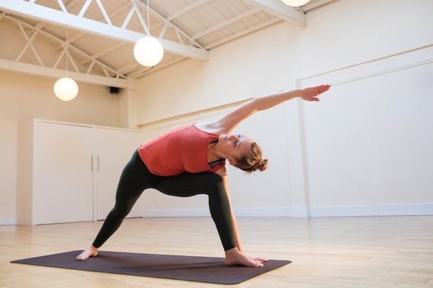 Woman performing extended side angle pose on exercise mat