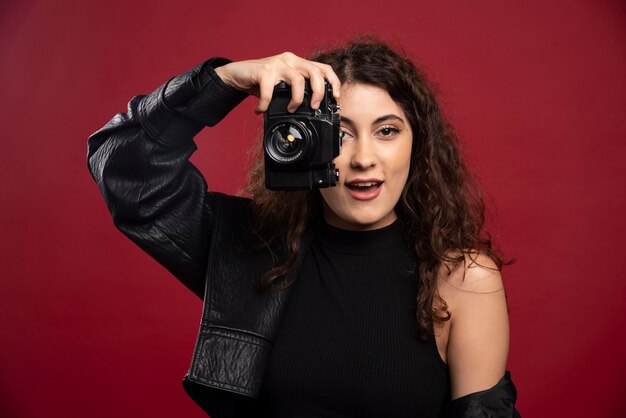 Woman photographer in all black outfit taking pictures with a camera .