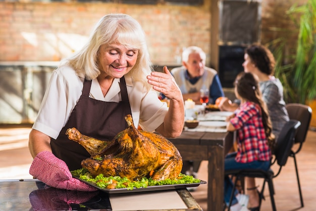 Free photo woman in pinafore smelling baked ham