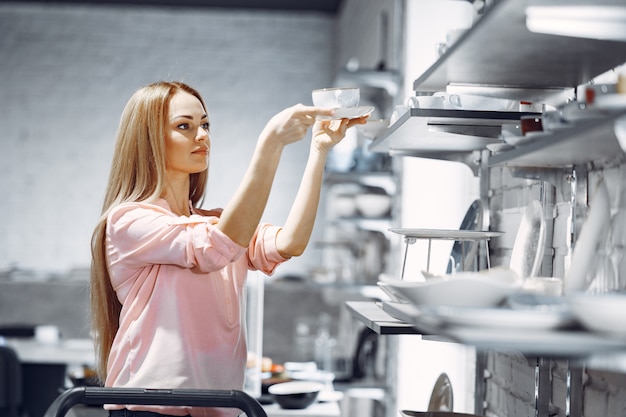 Woman in a pink blouse buys dishes in the store