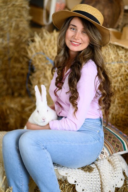 Woman in pink shirt playing with a white bunny rabbit