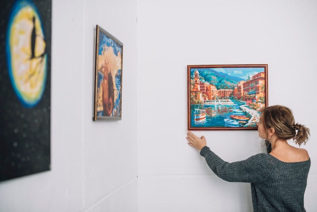 Woman placing painting on wall