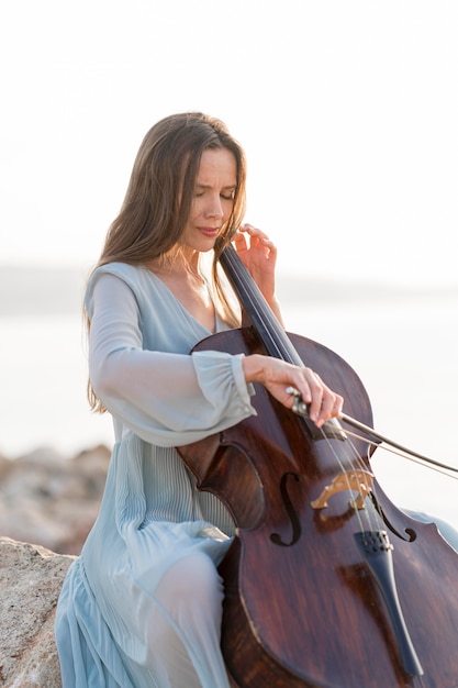 Free Photo woman playing cello on rocks outdoors