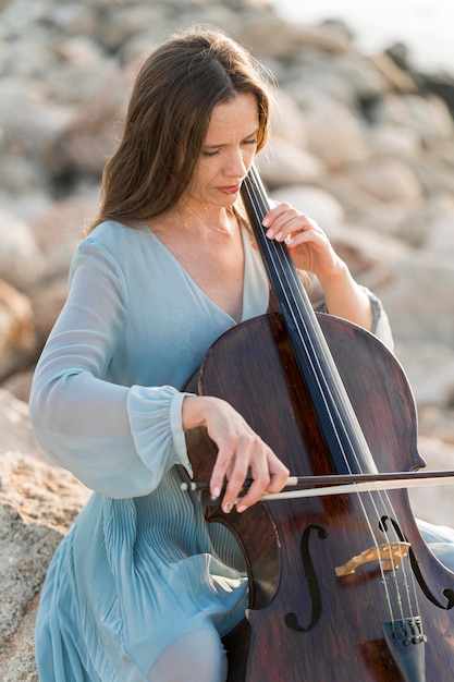 Woman playing cello on rocks