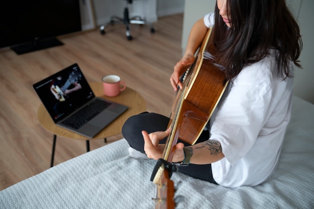 Free photo woman playing guitar at home during quarantine