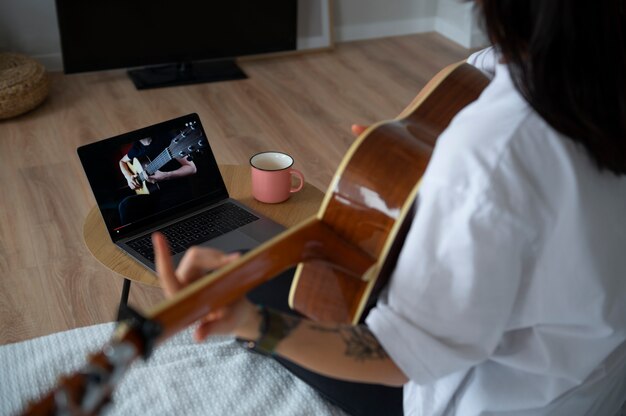 Free Photo woman playing guitar at home during quarantine