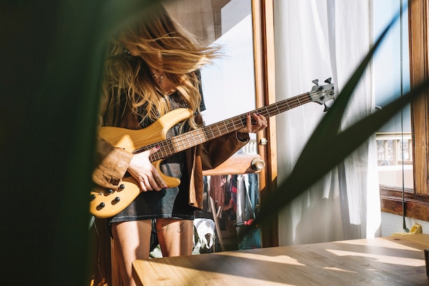 Woman playing guitar in light room