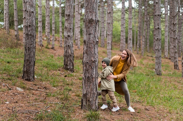 Free photo woman playing with her son in the forest