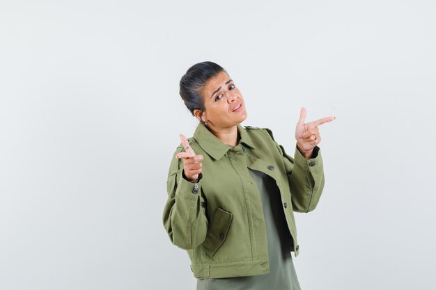 Woman pointing away in jacket, t-shirt and looking confident