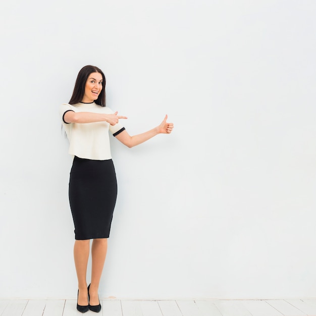 Woman pointing finger away and showing thumb up