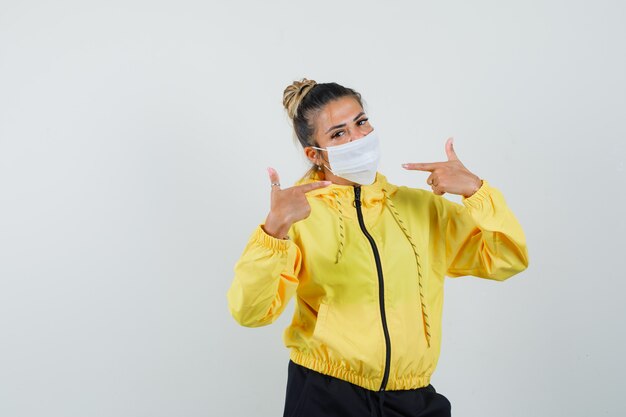 Woman pointing at her mask in sport suit front view.