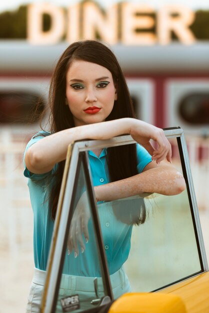 Woman posing in retro style next to car