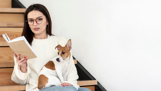 Woman posing on stairs with book and her dog