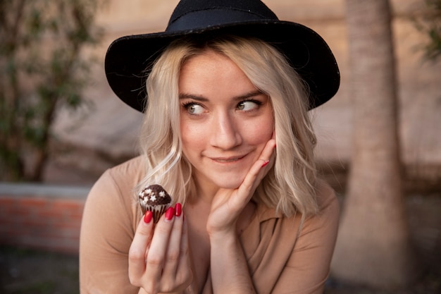 Free photo woman posing while holding a cupcake