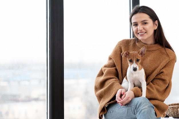 Woman posing while holding dog in her lap