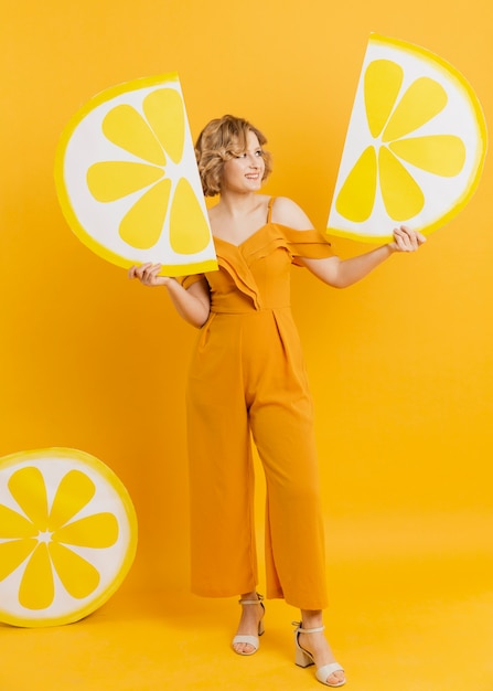 Free photo woman posing while holding lemon slices decorations