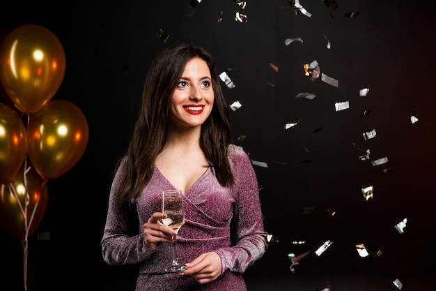 Woman posing with champagne glass and confetti at party