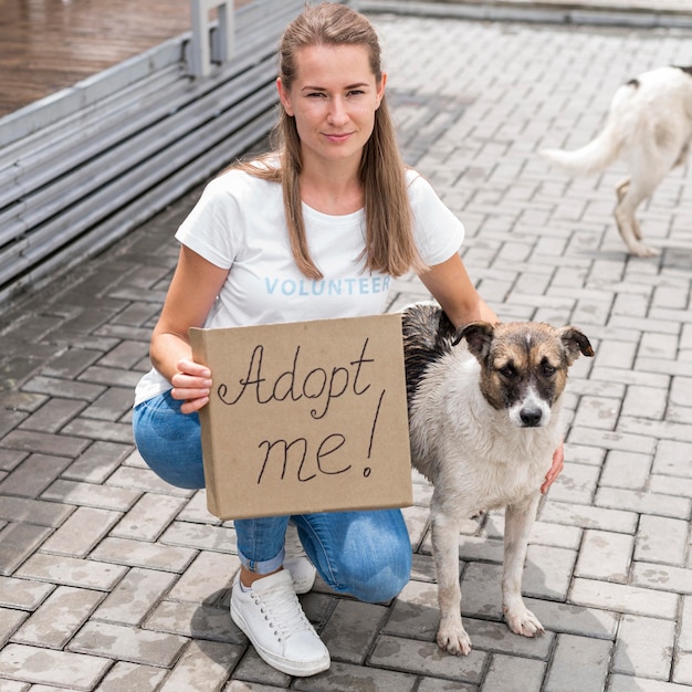 Woman posing with dog and holding adopt me sign for pet