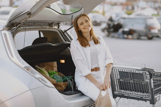 Woman posing with a shopping bag by her car