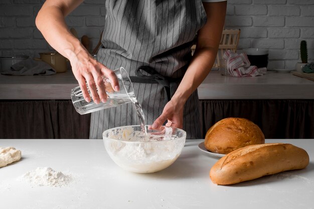 Woman pouring water over dough