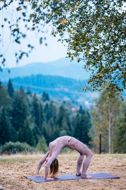 Free Photo a woman practices yoga at the morning in a park on a fresh air.