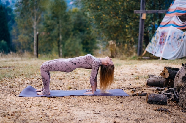 Free photo a woman practices yoga at the morning in a park on a fresh air.