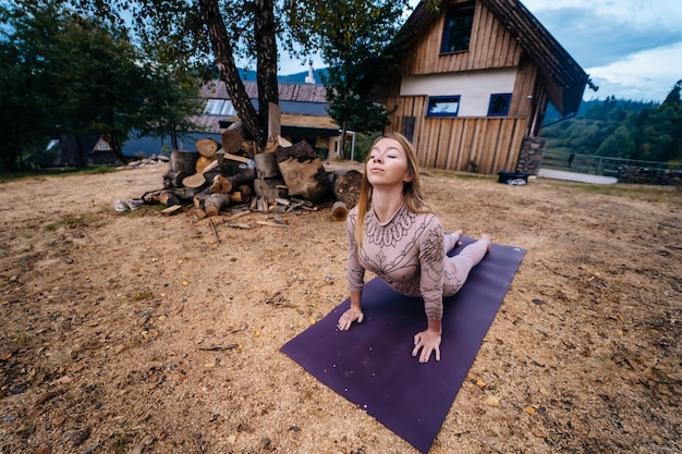 Free photo a woman practices yoga at the morning in a park on a fresh air.