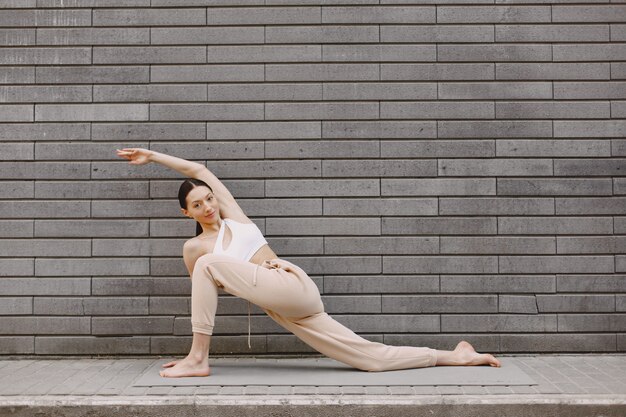 Woman practicing advanced yoga against a dark urban wall