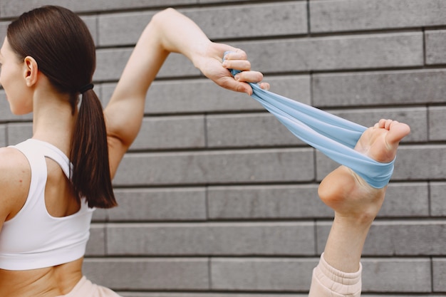 Woman practicing advanced yoga against a dark urban wall