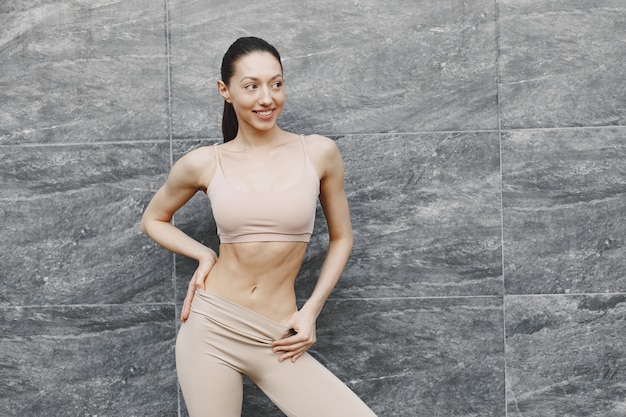 Woman practicing advanced yoga against a dark urban wall