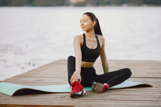 Woman practicing advanced yoga by the water