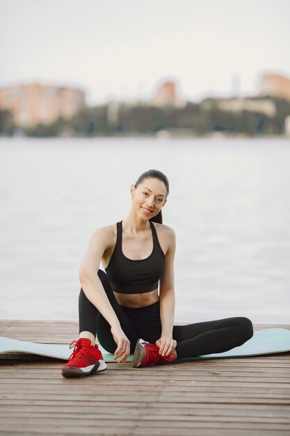 Woman practicing advanced yoga by the water