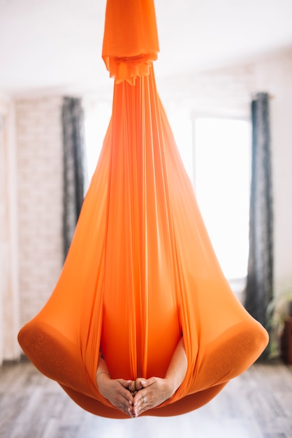 Woman practicing aero yoga in orange hammock