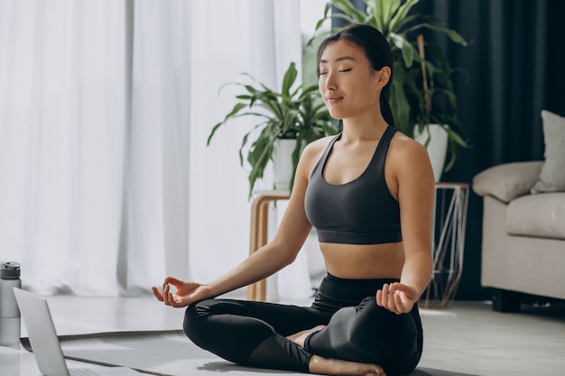 Woman practicing yoga on mat at home