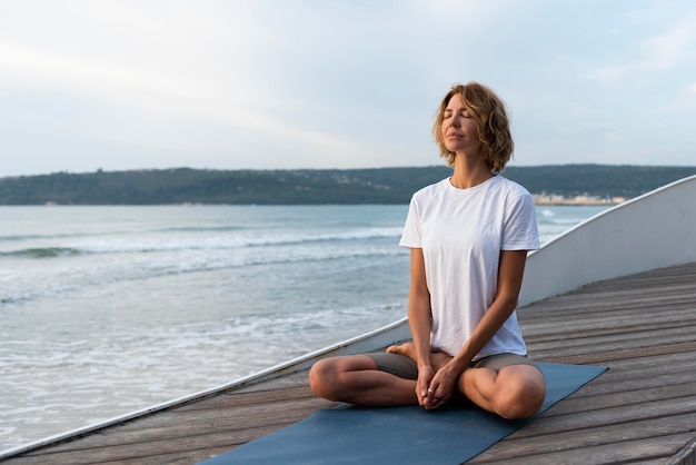 Free photo woman practicing yoga pose near sea