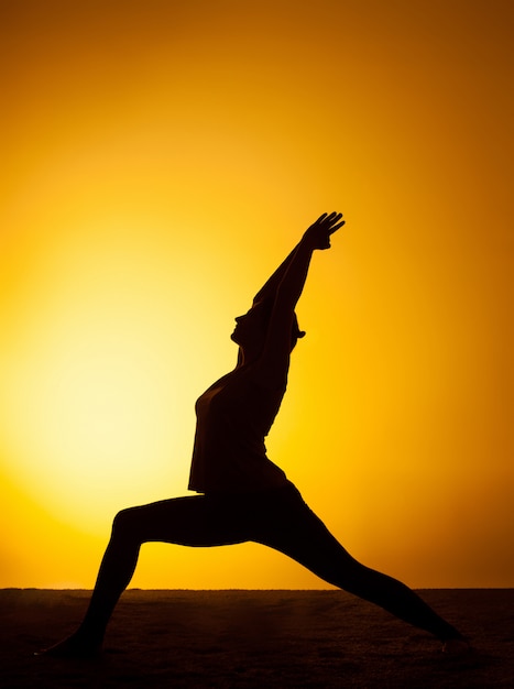 The woman practicing yoga in the sunset light