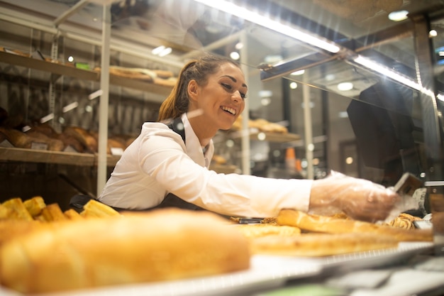 Woman preparing bread for sale in supermarket bakery department