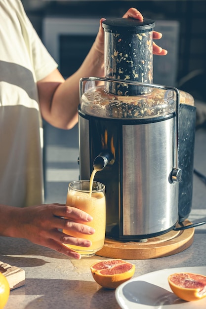 Free photo woman preparing fresh orange juice for breakfast in kitchen