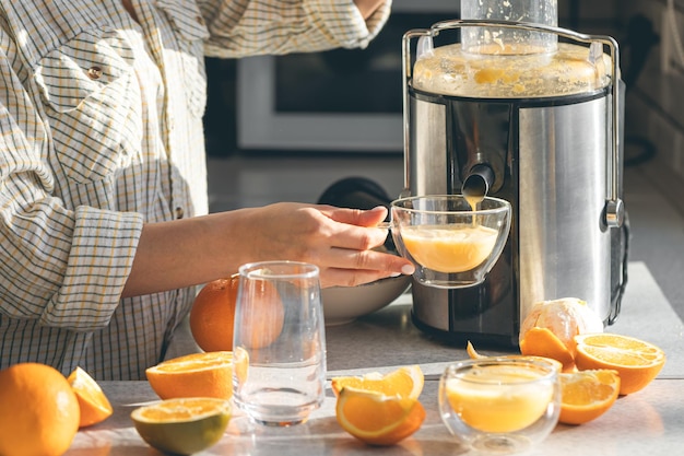 Free photo woman preparing fresh orange juice for breakfast in kitchen